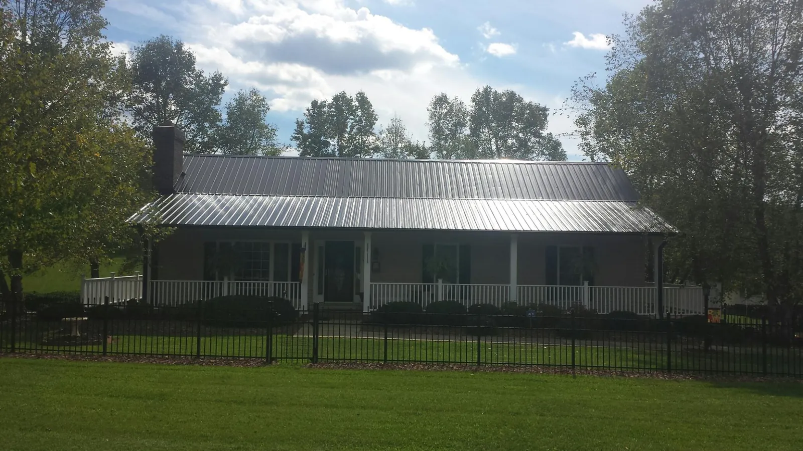 Gray metal roof on a brick ranch with a full width front porch — Gutter Guard Installation work by our crew in Carrabelle