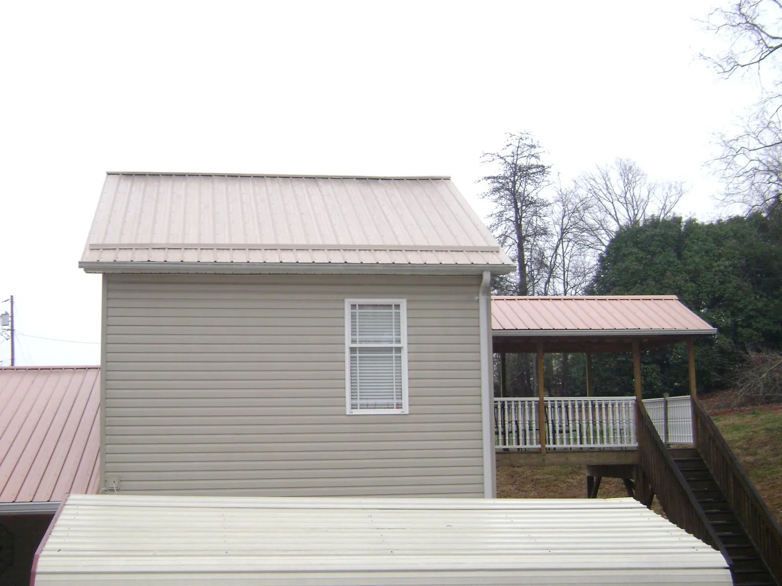 Tan metal roofs on a two story addition and attached porch, from a Roof Replacement job in Carrabelle